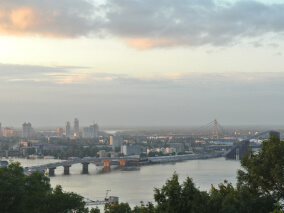 Vista panorâmica de cidade à beira de um rio com pontes e edifícios ao fundo